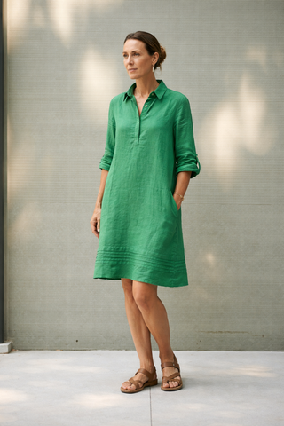 Woman wearing a green FABULOUS PREMIUM LINEN  dress standing against a neutral wall.